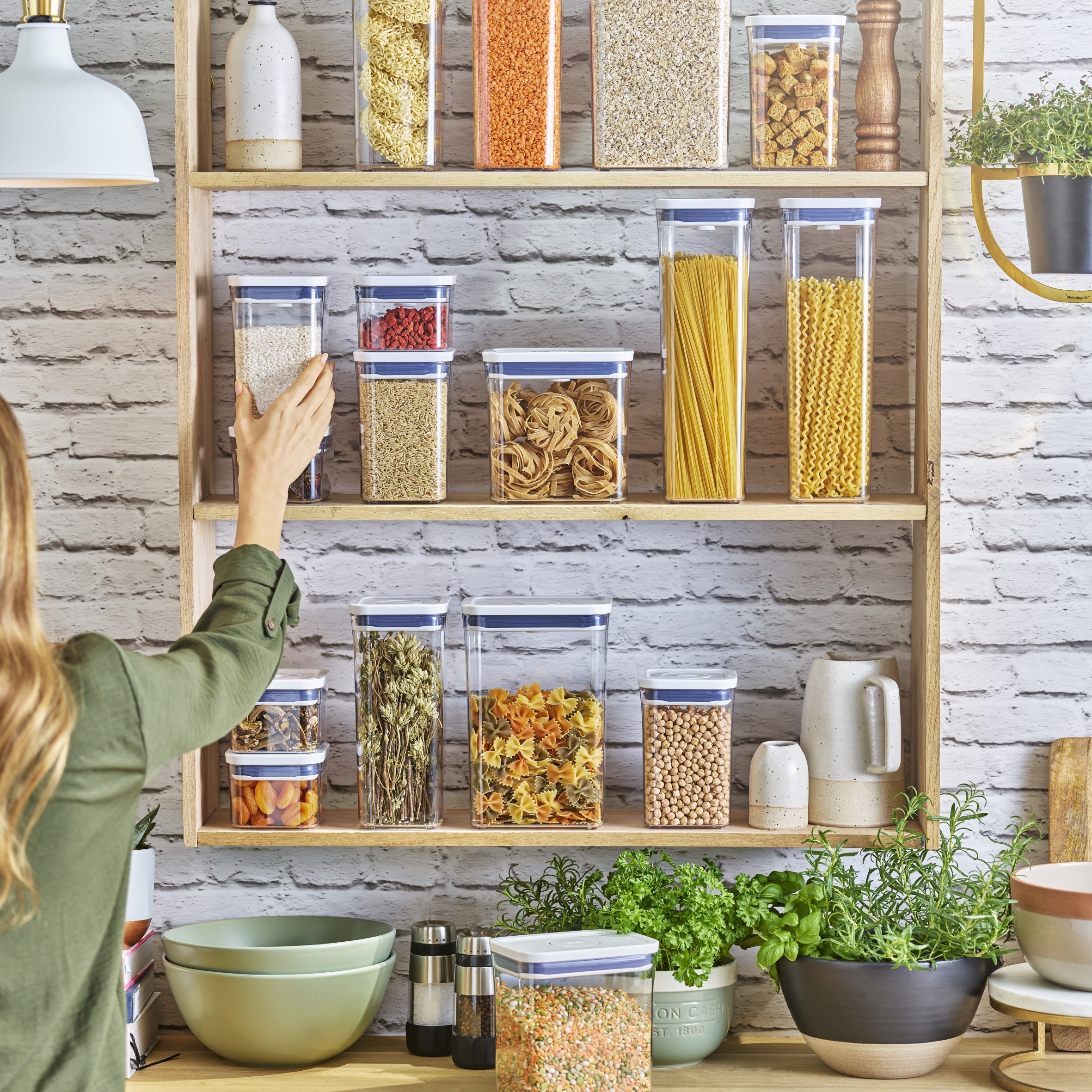 OXO POP Containers being arranged on open shelving in a contemporary kitchen setting.